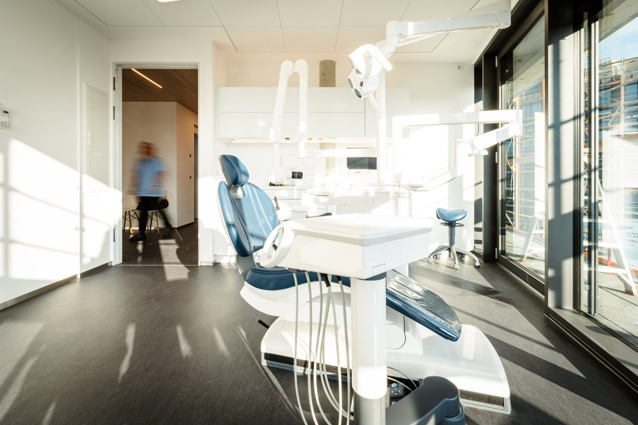 Zahnmedizin an der Lokhalle – zahnärztliche Kompetenz mit Herz 5 Lichtdurchflutetes Behandlungszimmer mit blauem Behandlungsstuhl und großen Fenstern.